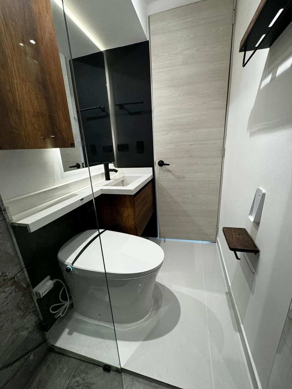 Baño con mueble en roble, lavamanos blanco y espejo LED