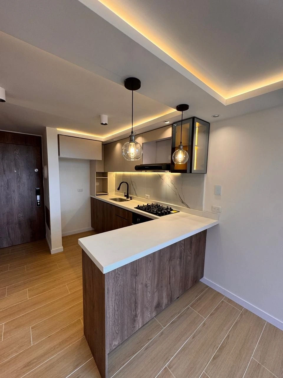 Cocina con barra, muebles oscuros y lámparas de globo