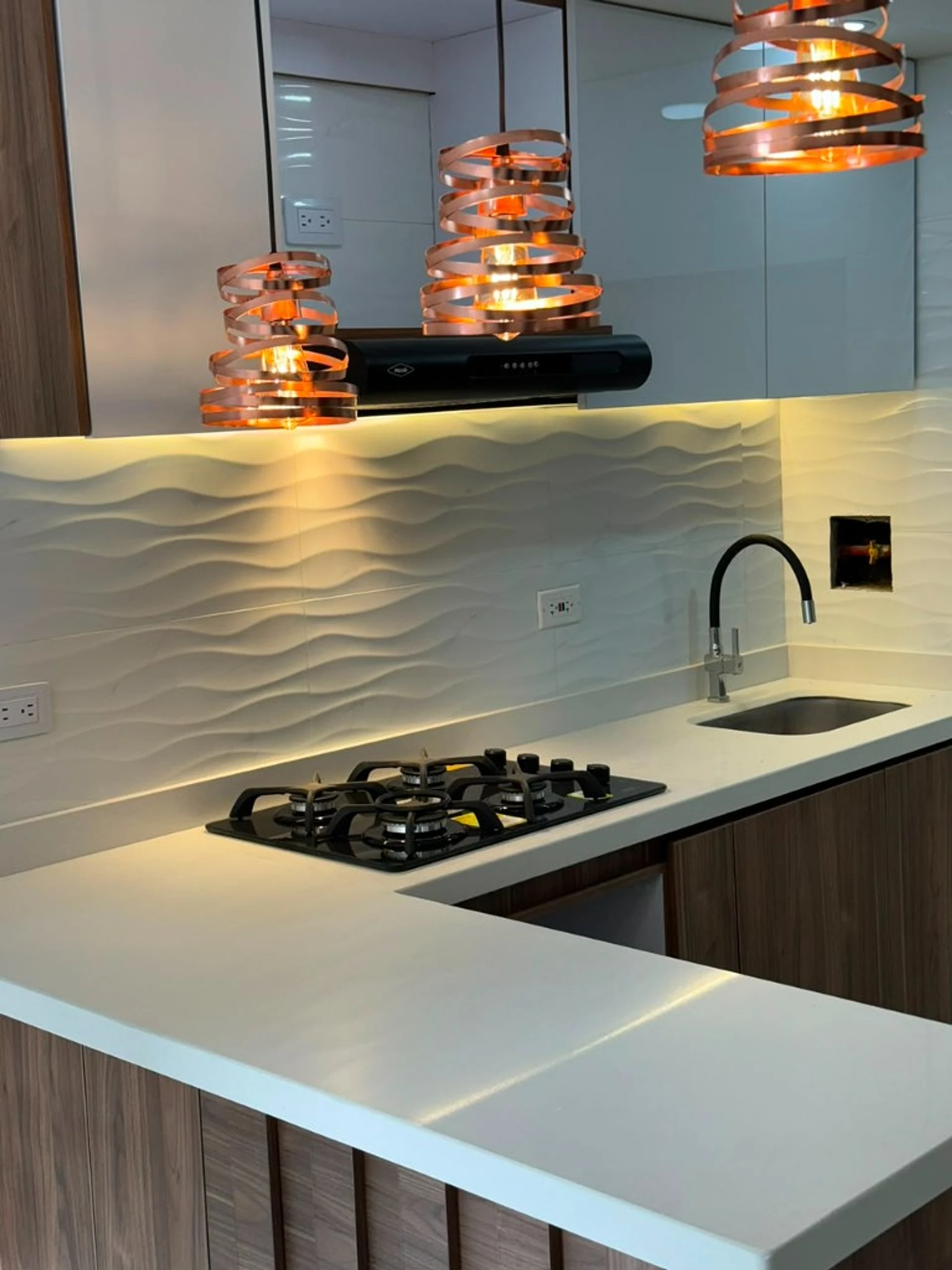 Cocina con lámparas de cobre, salpicadero en ola y cubierta blanca