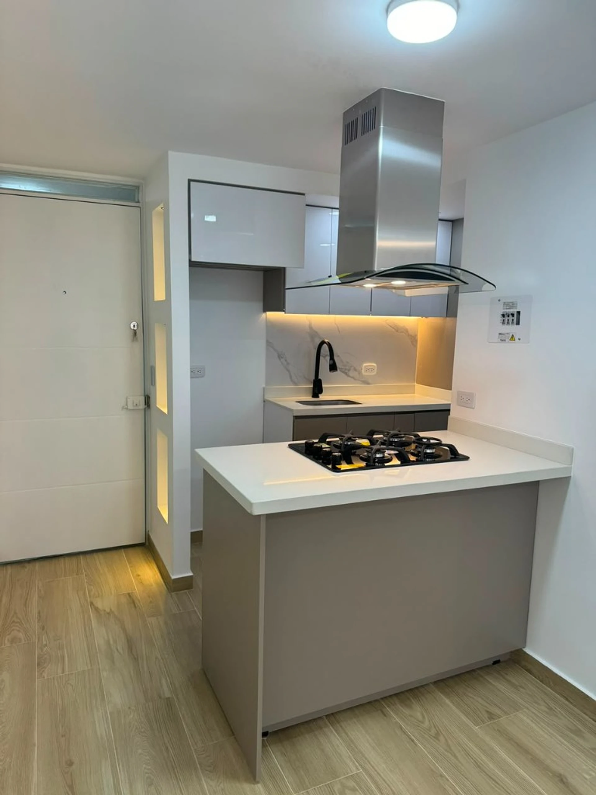Isla de cocina con estufa, campana de acero y cubierta blanca
