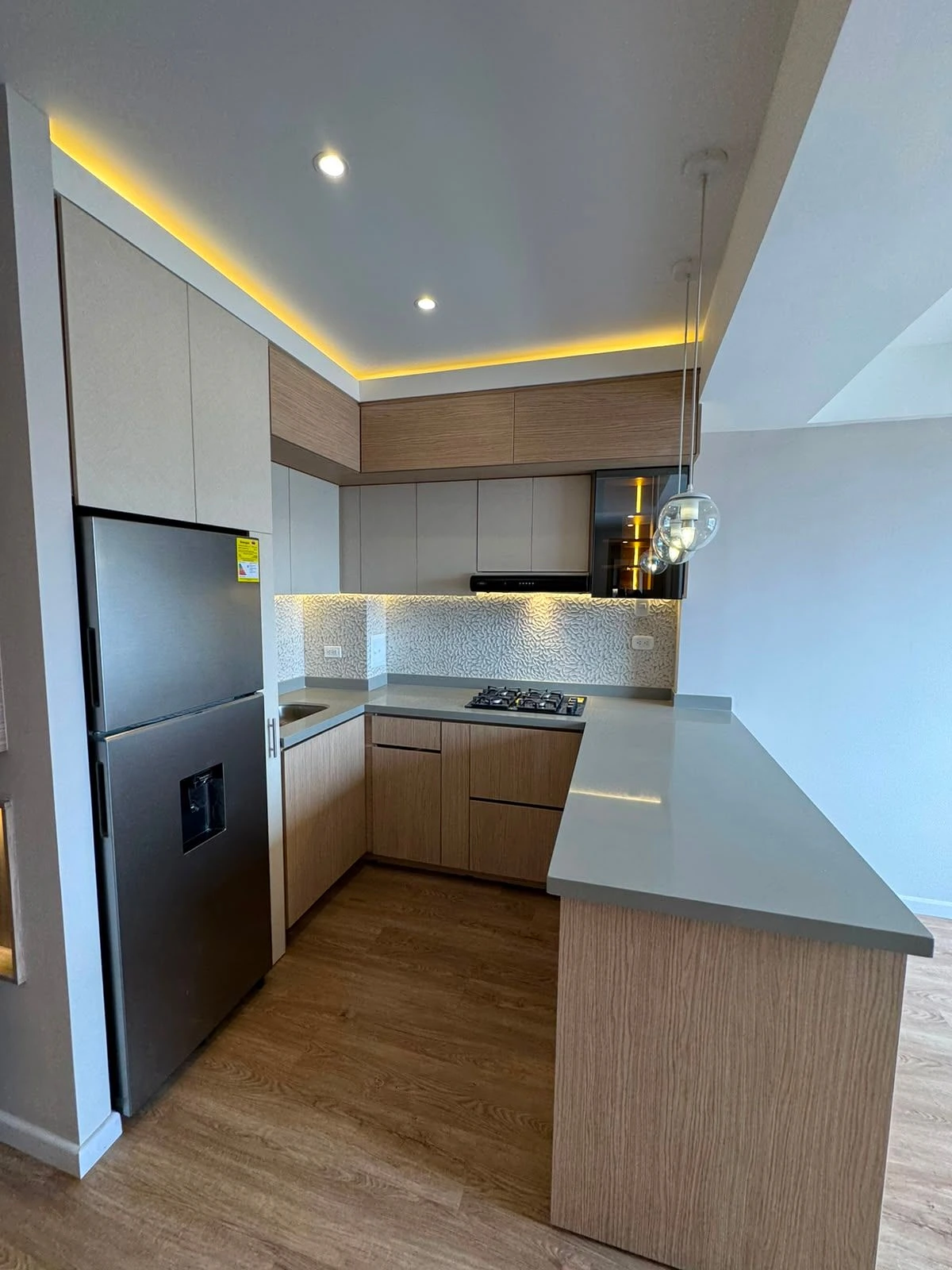 Cocina con isla, lámparas de globo y cubierta gris en Bogotá