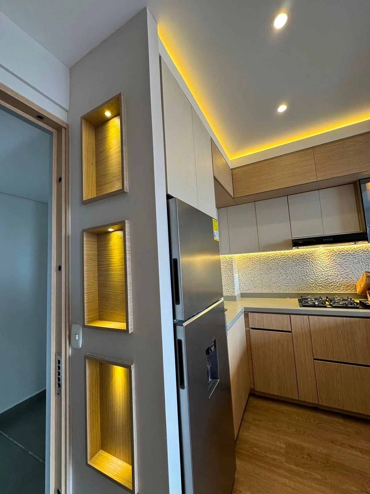 Cocina a medida con nichos iluminados, nevera y cenefa LED en Bogotá